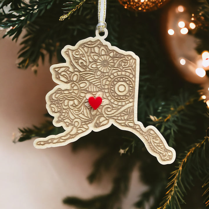 Wooden Alaska ornament with white and gold ribbon and red heart.