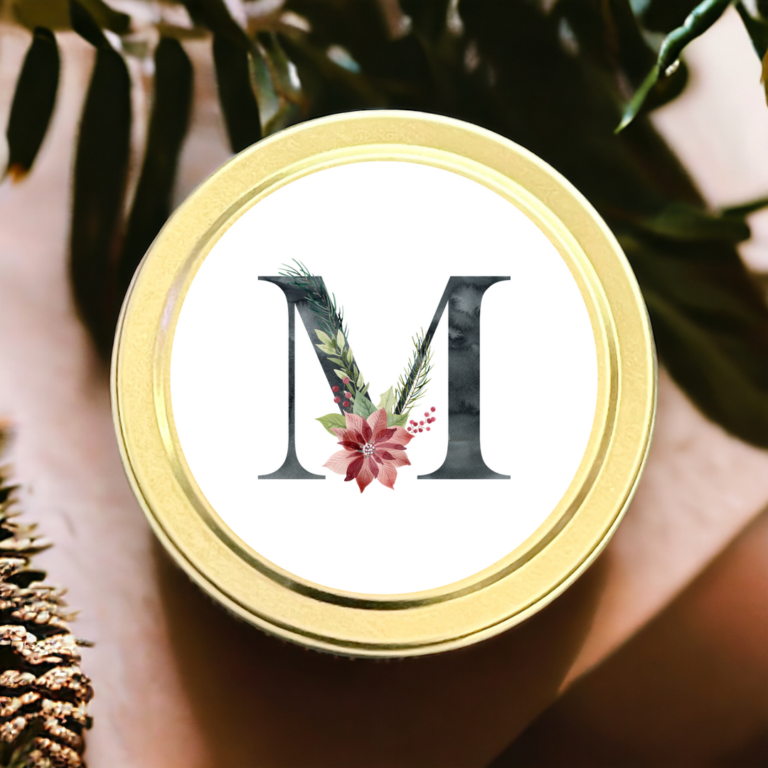 Gold tin candle with the initial M with a Christmas floral theme.