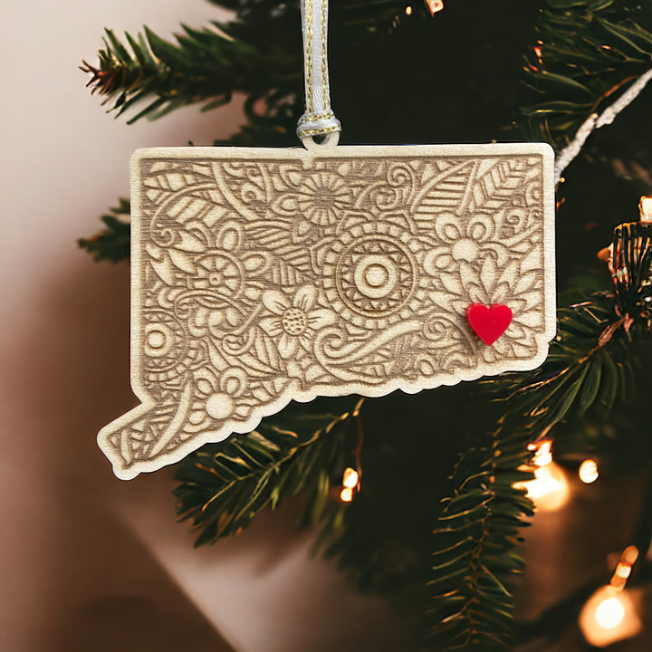 Wooden Connecticut ornament with white and gold ribbon and red heart.