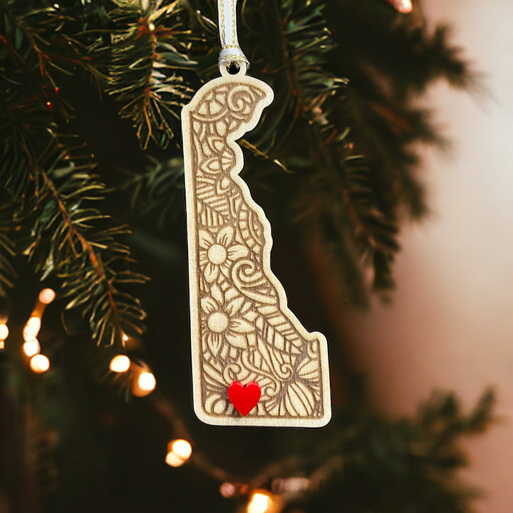 Wooden Delaware ornament with white and gold ribbon and red heart.