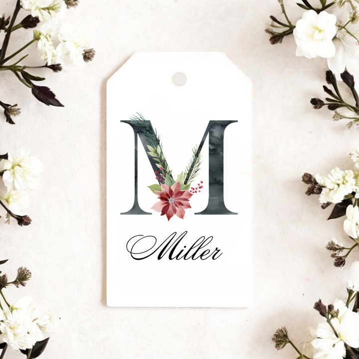 A gift tag with the initial M with a red poinsettia design and the last name Miller.