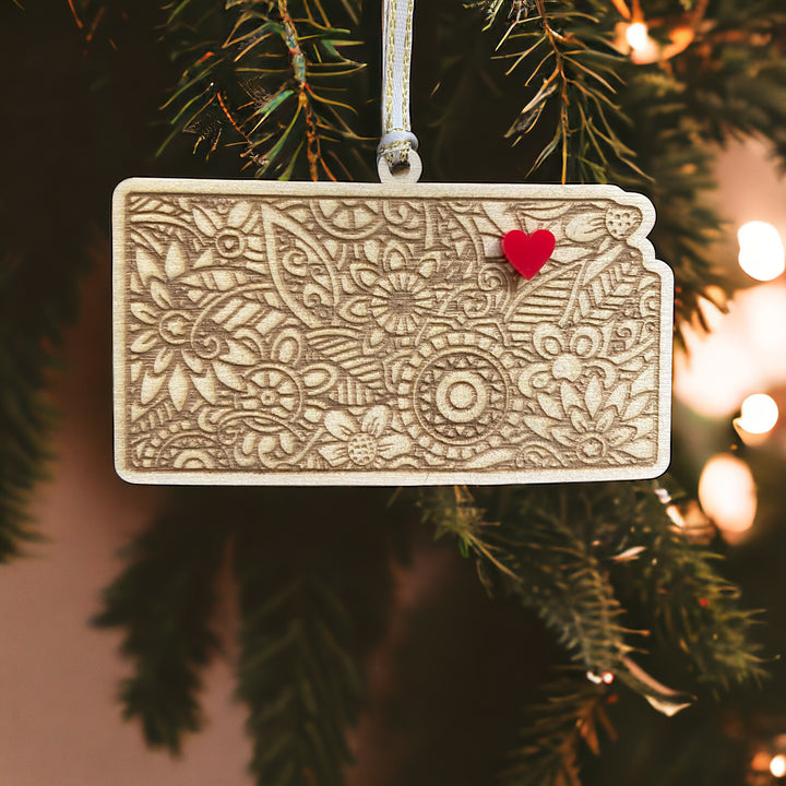 Wooden Kansas ornament with white and gold ribbon and red heart.