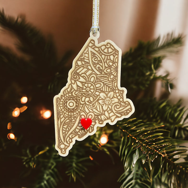 Wooden Maine ornament with white and gold ribbon and red heart.