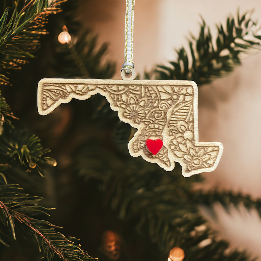 Wooden Maryland ornament with white and gold ribbon and red heart.