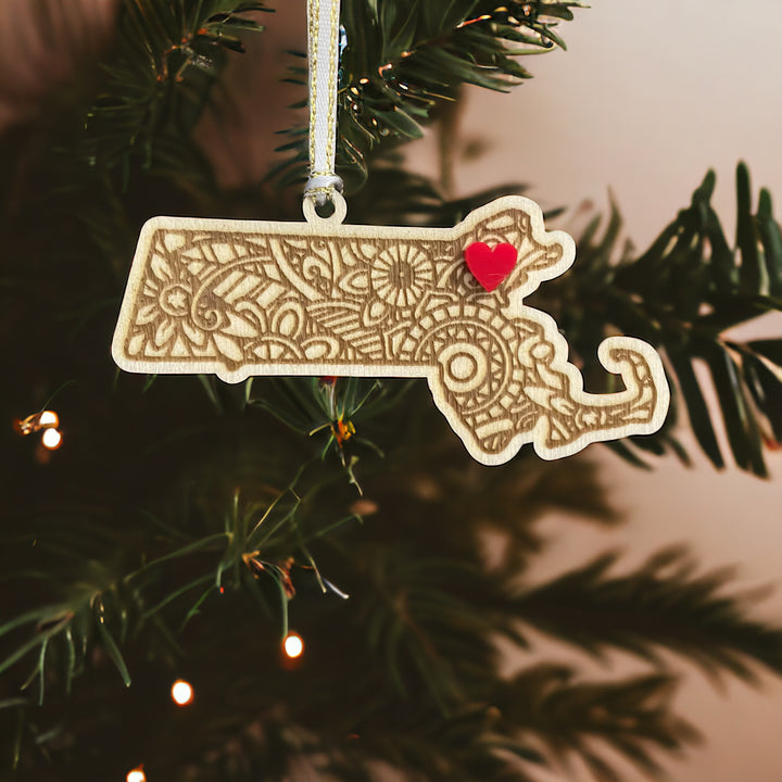 Wooden Massachusetts ornament with white and gold ribbon and red heart.