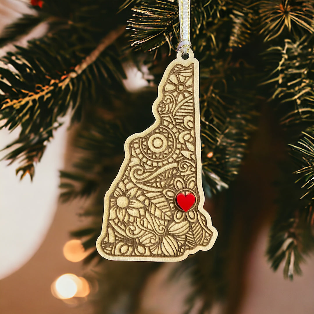 Wooden New Hampshire ornament with white and gold ribbon and red heart.