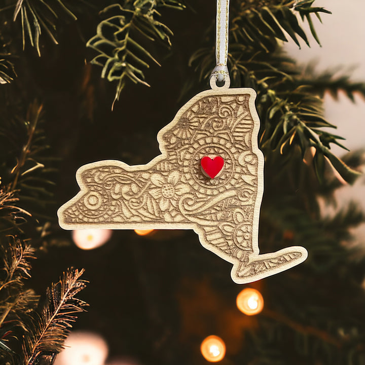 Wooden New York ornament with white and gold ribbon and red heart.