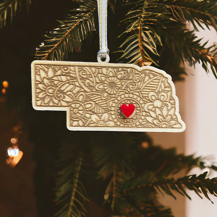 Wooden Nebraska ornament with white and gold ribbon and red heart.