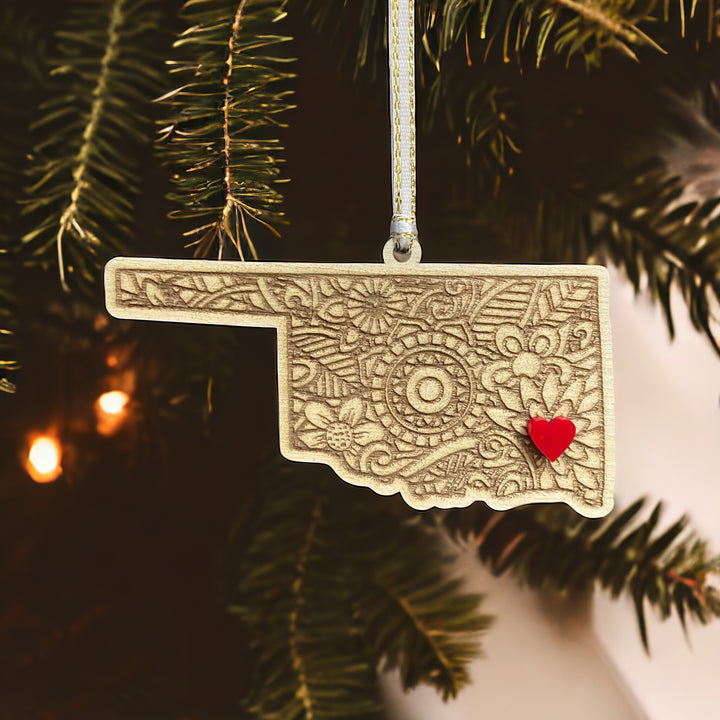 Wooden Oklahoma ornament with white and gold ribbon and red heart.