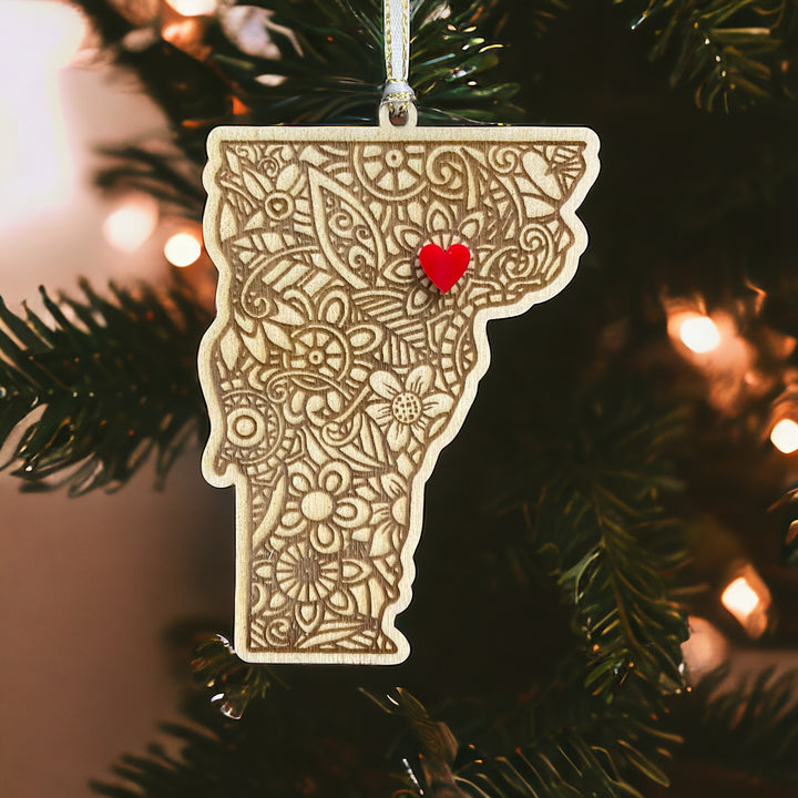 Wooden Vermont ornament with white and gold ribbon and red heart.