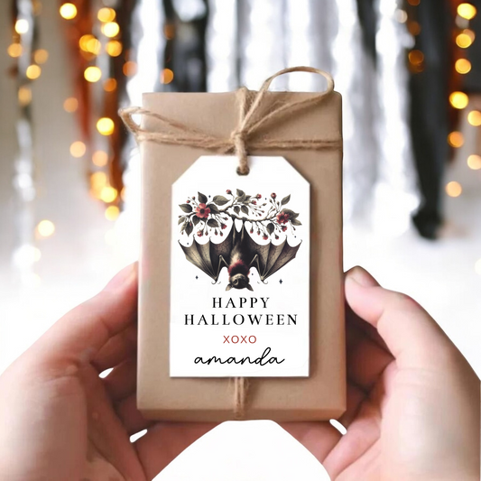 A small gift box with an upside down bat hanging off a floral branch.