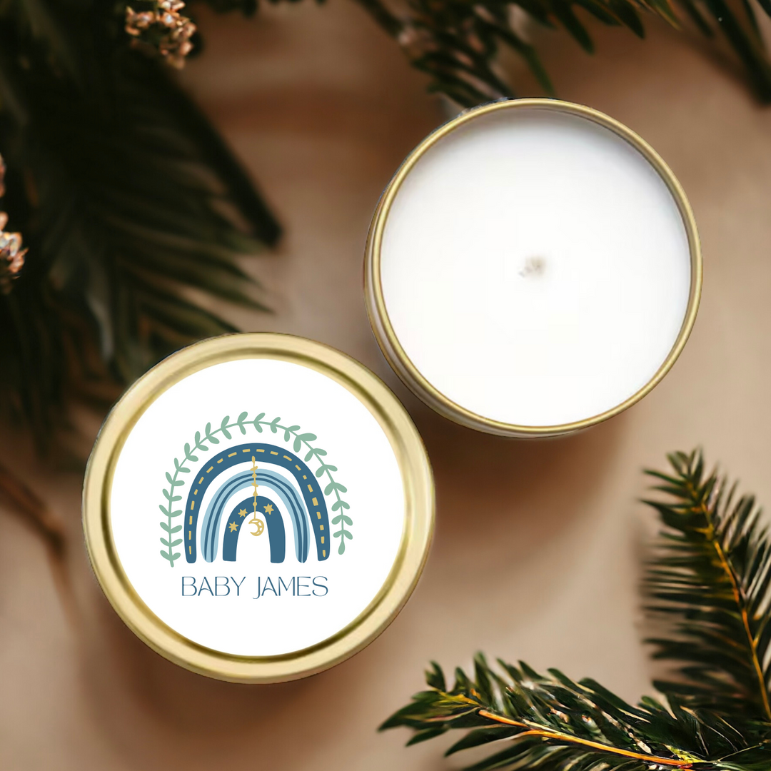 A gold tin candle with a blue rainbow label and a baby's name.