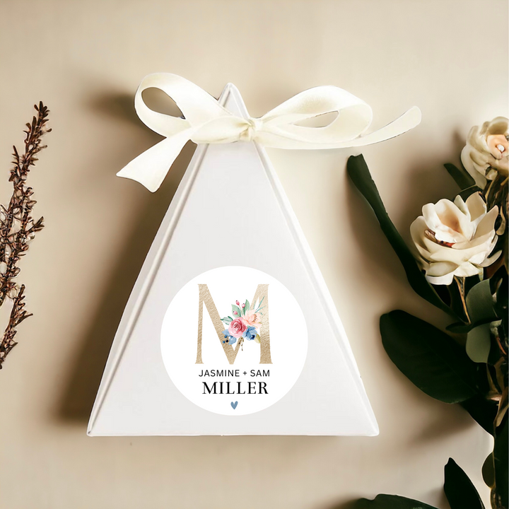 Triangular gift box with white bow on top and personalized label.