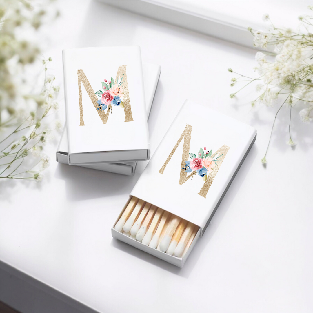 Matchboxes with a gold M decorated in flowers.