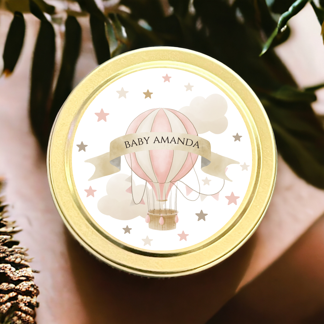 A gold tin candle with a personalized baby shower label.