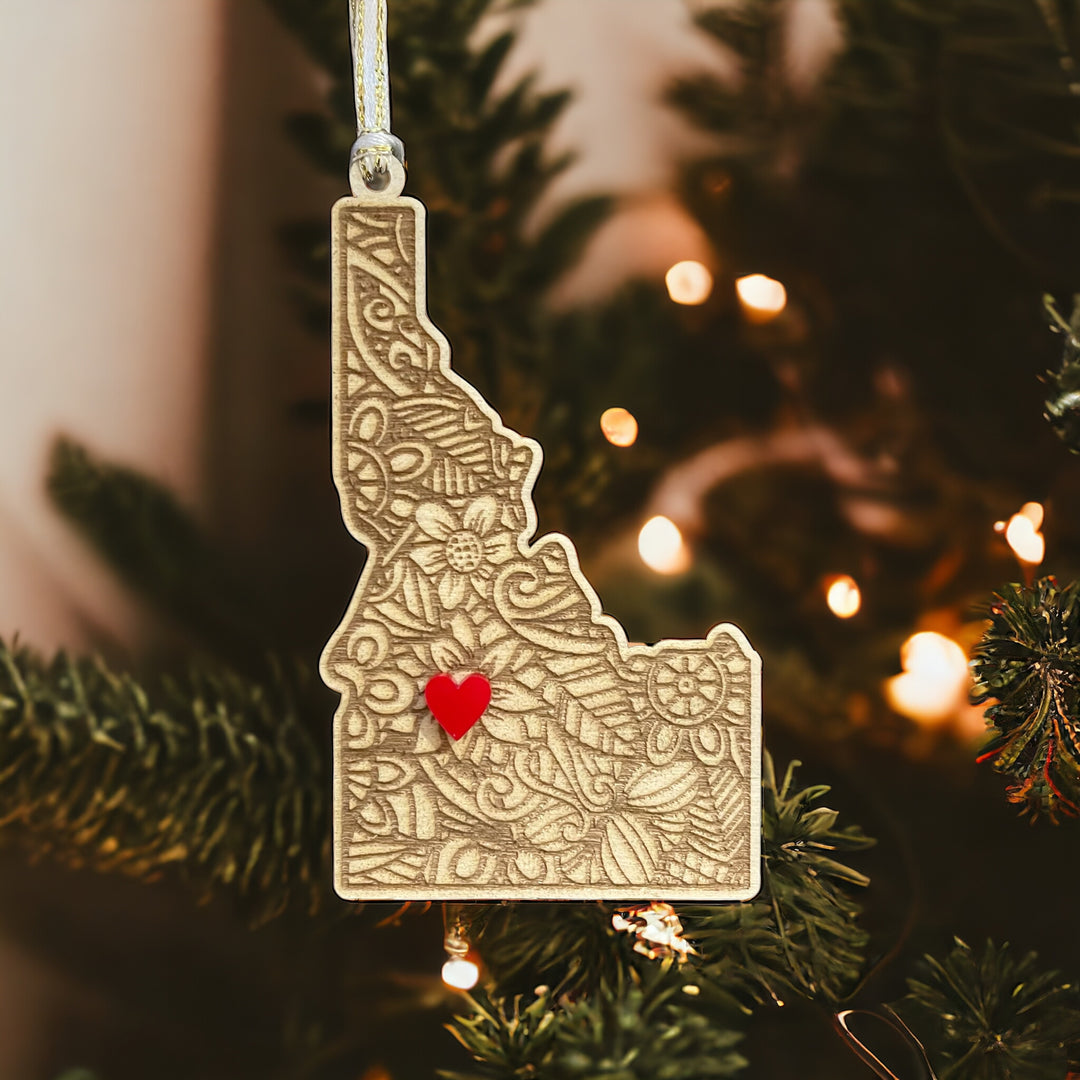 Wooden Idaho ornament with white and gold ribbon and red heart.