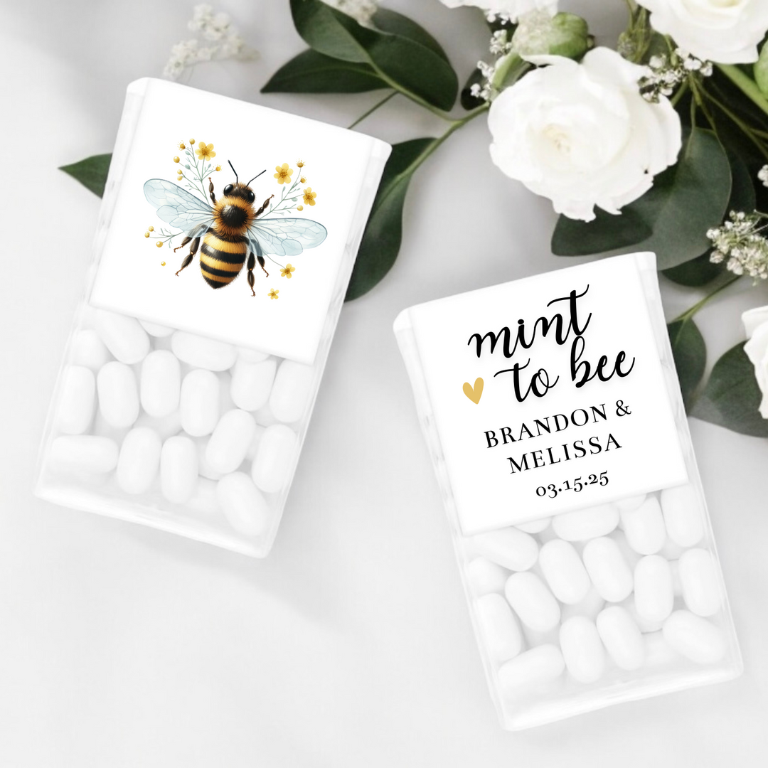 Two tic tac boxes with a picture of a bee and mint to bee, a couple's name and date.