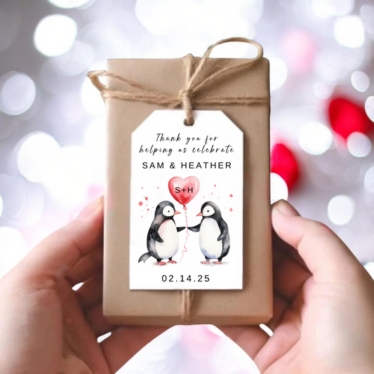 A small gift box with a personalized tag of two penguins holding a red balloon.