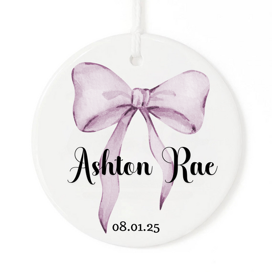 White Christmas ornament keepsake with watercolor bow, baby's name and birth date.