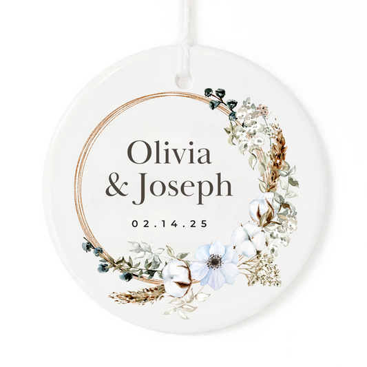 A white Christmas ornament with boho wreath, personalized names and wedding date.