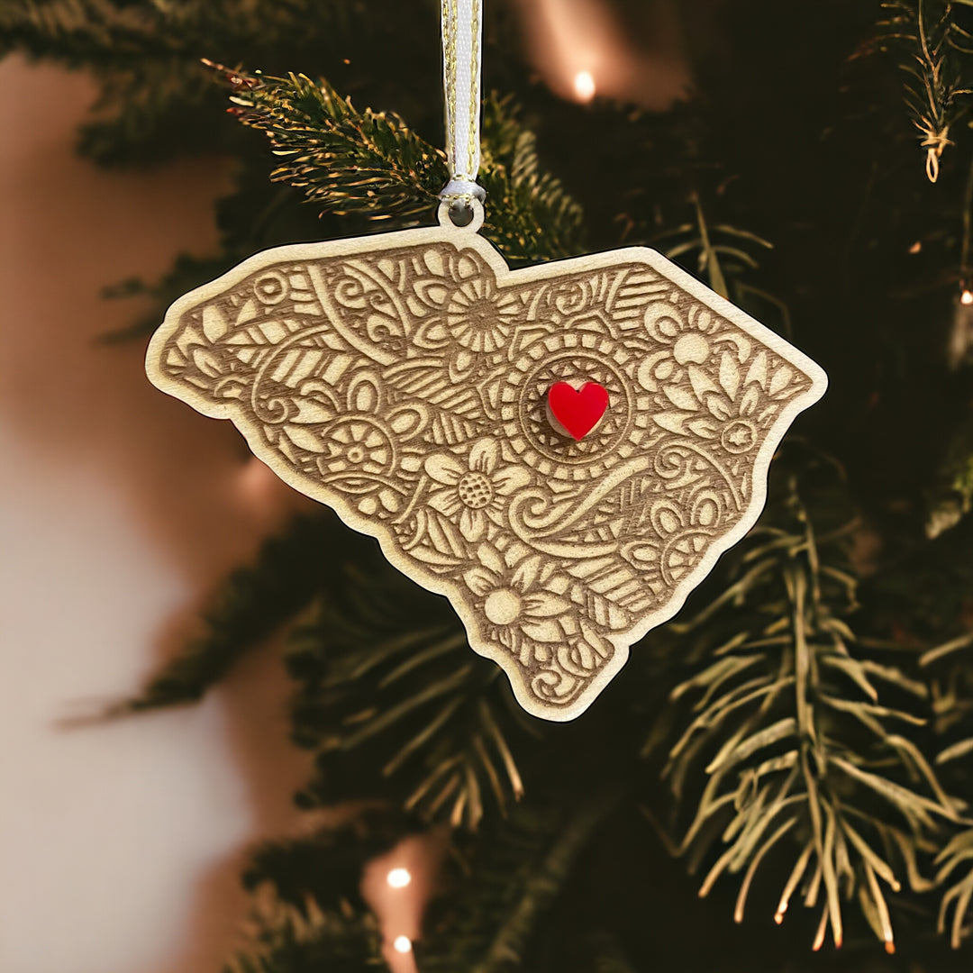 Wooden South Carolina ornament with white and gold ribbon and red heart.